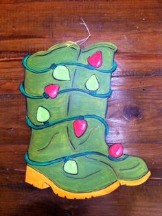 a painting of a green boot with red hearts on it's side, sitting on a wooden floor