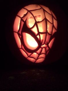 a pumpkin carved to look like a spiderman's web with its eyes open