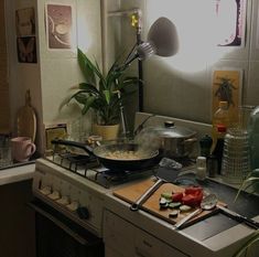 a stove top oven sitting inside of a kitchen next to a pot and pan filled with food