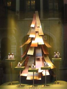 a christmas tree made out of pieces of paper on display in a store front window