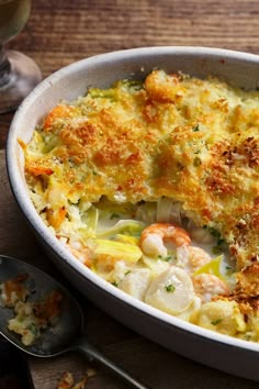 a casserole dish with shrimp and scallops in it on a wooden table