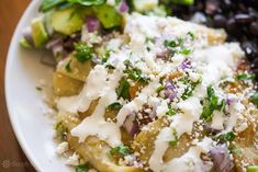 a white plate topped with pasta covered in cheese and sauce next to black olives