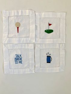 four embroidered napkins with different types of golf related items on them, one has a red flag and the other has a blue cup