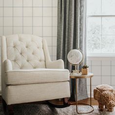 a white chair sitting next to a window in a room with a rug on the floor