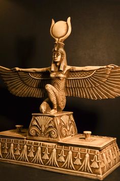 an egyptian statue is shown in gold on a black background with the light shining through it