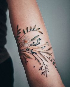 a woman's arm with flowers and leaves tattooed on the left side of her arm