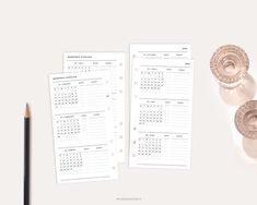 two blank calendars next to a pencil on top of a white surface with an image of the same one