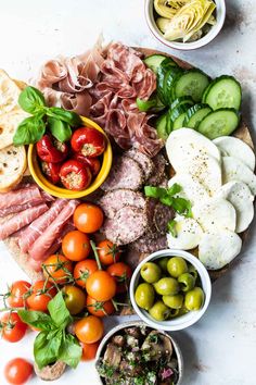 an assortment of meats, vegetables and bread on a platter with olives