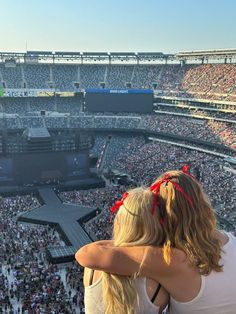 two women sitting on the shoulders of each other in front of an audience at a concert