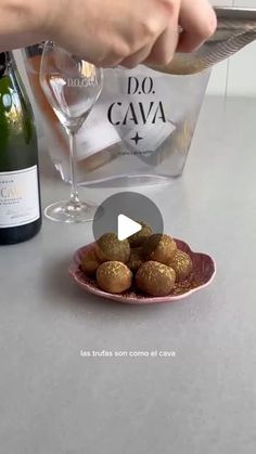 a person pouring wine into a glass with some food on the plate next to it