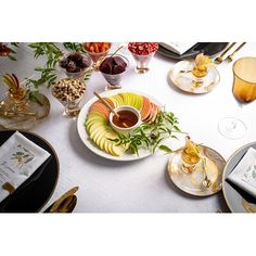 the table is set with an assortment of fruit and wine glasses, silverware, and plates