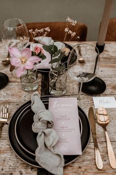 a place setting with silverware, napkins and flowers