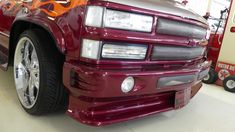 the front end of a red truck with flames painted on it's hood and bumper