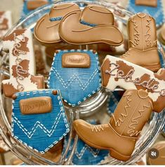 cookies in the shape of cowboy boots and booties on a glass platter with blue napkins