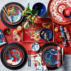 a red table topped with lots of plates and bowls