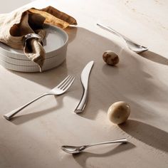 an empty plate, fork and knife on a table with other utensils next to it