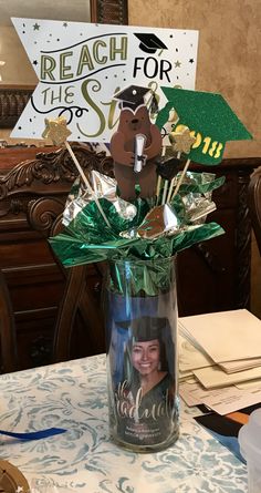 a graduation centerpiece in a glass vase on a table with a sign and decorations