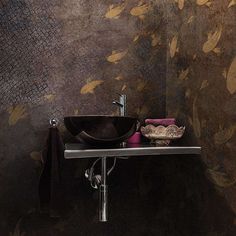 a bathroom sink sitting under a mirror next to a wall covered in gold leaf designs