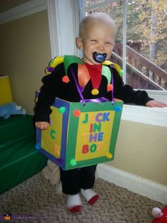 a toddler dressed up as a clown with a box on his head and mouth