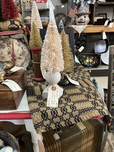 several small trees are on display in a room full of other christmas decorations and antiques