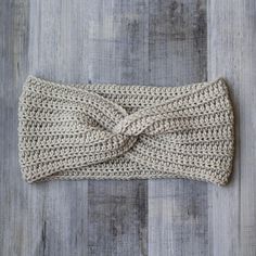 a crocheted headband with a knot on the side sitting on a wooden floor