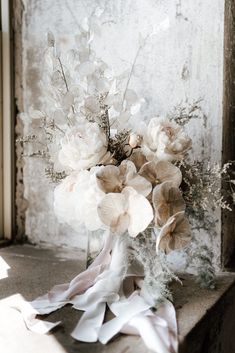 a bouquet of flowers sitting on top of a window sill next to a wall