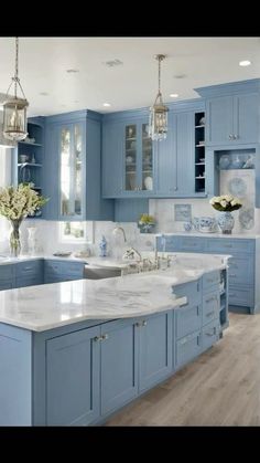 a large kitchen with blue cabinets and white counter tops on the island in front of the sink