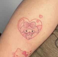 a hello kitty tattoo on the arm of a woman's left arm, with a heart and bow