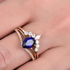 a woman's hand wearing a ring with an oval blue stone and diamond accents