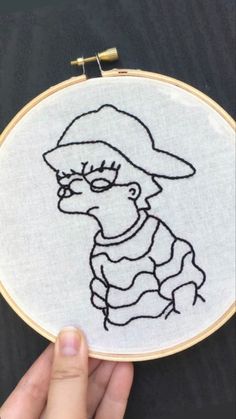 a hand embroidered picture of a person wearing a hat and glasses, with the outline of a cartoon character on it