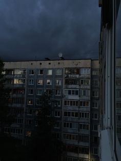 an apartment building is lit up by the dark sky at night, with windows and balconies visible