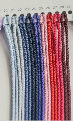 several different colors of braided rope on a table with measuring tape in the background