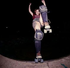 a young woman riding a skateboard on top of a cement ramp in the dark