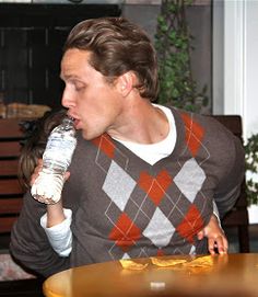 a man sitting at a table drinking from a bottle