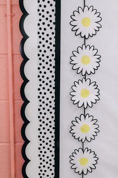 the wall is decorated with black and white polka dots, daisies, and scalloped paper