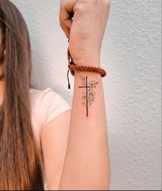 a woman with a tattoo on her arm holding up a cross and flower wristband