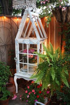 an old window is transformed into a planter in the garden with fairy lights strung from it