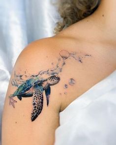 a woman with a tattoo on her shoulder that has a sea turtle flying through the air