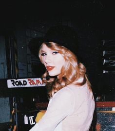 a woman with red hair wearing a hat and posing for a photo in front of a keyboard