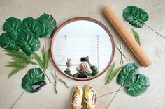 a person taking a selfie in front of a mirror with green leaves and scissors