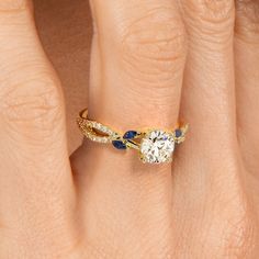 a woman's hand with a diamond and blue sapphire ring on her finger,