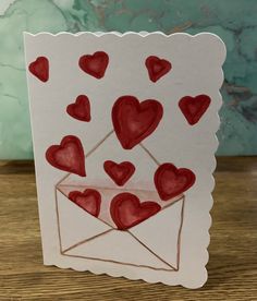 a handmade card with hearts coming out of an envelope on top of a table