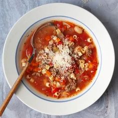 a bowl of soup with meat, noodles and parmesan cheese on the side