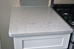 a white kitchen counter top next to an oven