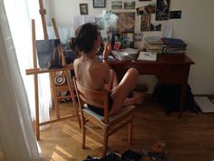 a woman sitting on a chair in front of a desk with pictures and other items