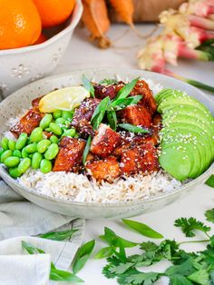 a white bowl filled with rice and vegetables next to oranges, avocado