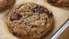 chocolate chip cookies with sea salt sprinkled on top are lined up on a baking sheet