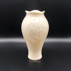 a white vase sitting on top of a black table