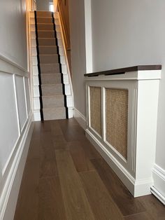 a dog door is on the side of a stair case next to a wooden floor