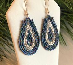 a pair of blue and white beaded earrings hanging from a christmas tree ornament